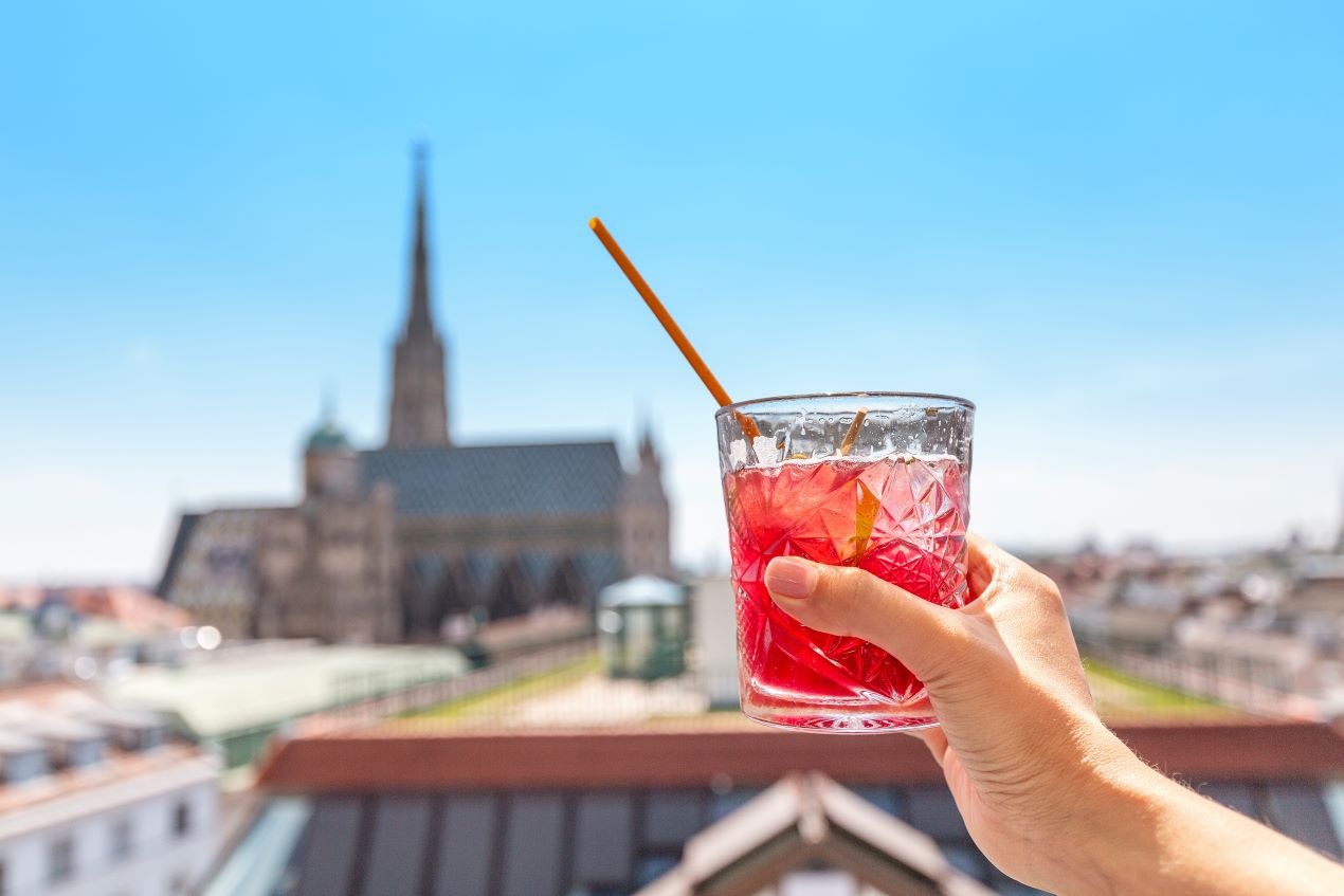 Ein Cocktailglas auf einer Rooftop-Bar mit Blick auf den Stephansdom – luxuriöse Erlebnisse in Wien, kombiniert mit diskreten Angeboten wie Escort Service Wien.