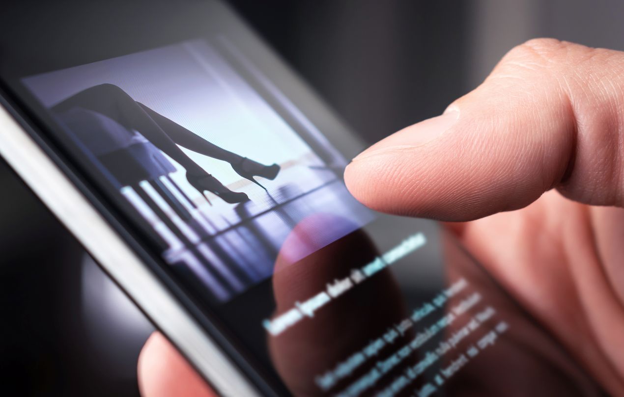 Nahaufnahme eines Smartphones mit Bild einer Frau in High-Heels, symbolisch fuer digitale Buchung von High-Class-Escort in Muenchen